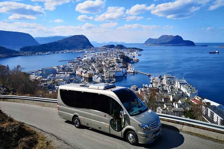 Company minibus parked on mountain road with city of Aalesund in the background.